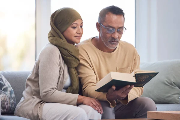 Muslim couple, reading Quran and spiritual with islam, hijab and book for faith, trust and learning scripture in home. Islamic man, woman and read religious book, support and learn on eid Mubarak.