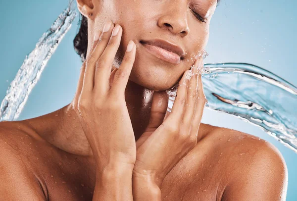 Face, water and skincare black woman for beauty, cosmetics and dermatology with youth glow or shine on blue studio background. Facial water splash, skin care and young model with beauty and manicure.