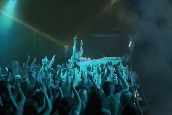 Crowd surfing. A stage diver being carried across the audience at a rock concert