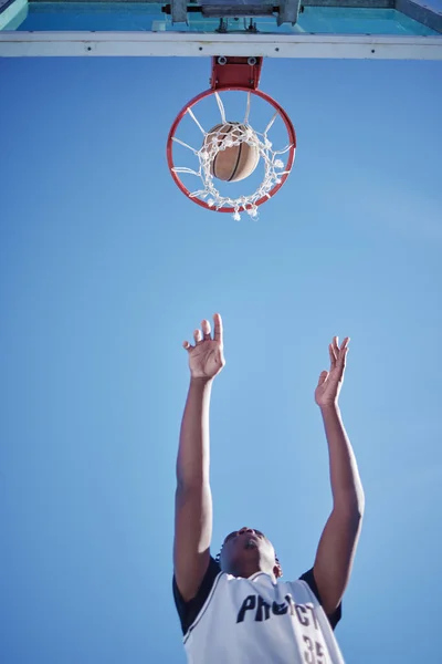 篮球比赛中的跳投 进球和人在场上玩的是一个低角度的游戏来模拟 运动员的动机 健身和健康的生活方式 外面有蓝天背景的专职体育人士 — 图库照片