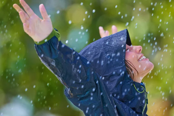 雨と一緒に 雨の中で両腕を伸ばして立つレインコートを着た若い女性 — ストック写真