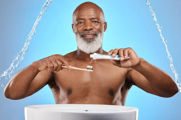 Water splash, dental and senior black man with a toothbrush and toothpaste for cleaning his teeth in studio. Face, portrait and elderly person brushing teeth or mouth on bathroom sink for self care.