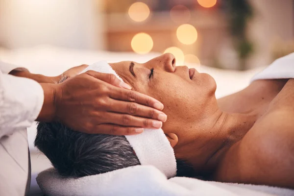 Wellness, health and massage, senior woman at a spa getting luxury beauty therapy and facial. Mature black woman, zen and masseuse massaging oil on head to help relax body and mind for stress relief