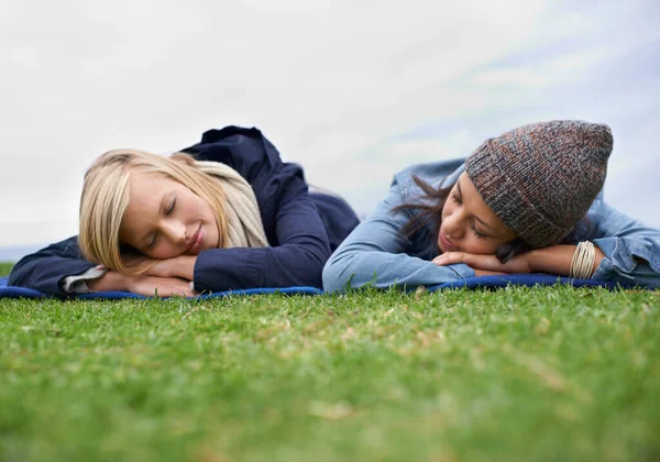 和我最好的朋友在一起很愉快两个年轻女人躺在外面的草坪上笑着 — 图库照片