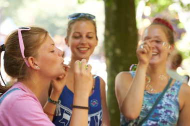 Umursamaz gençlik. Festivalde sosyalleşirken baloncuk çıkaran üç genç kadın