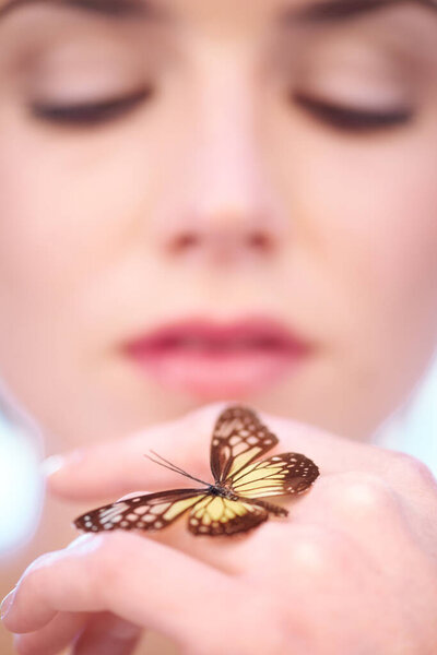 Eco-friendly skincare. A woman holding a butterfly on her hand