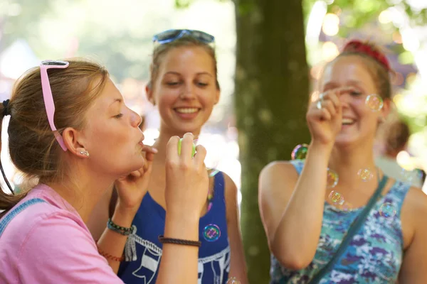 気の利いた若者 祭りで社交しながら泡を吹いている3人の若い女性 — ストック写真