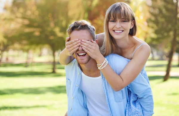 お互いの会社を楽しむ 男は彼のガールフレンドにピギーバックを与えながら 彼女は公園で彼の目をカバー — ストック写真