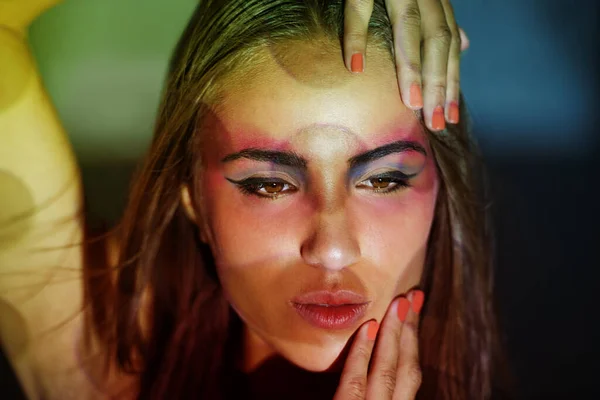 コンセプトを掲げる 彼女の顔に投影パターンと色を持つ若い女性のスタジオショット — ストック写真