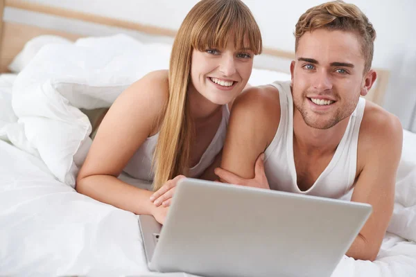 完璧な休暇を予約する ベッドでノートパソコンで働いてる若いカップルが — ストック写真
