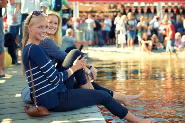 Cooling off. two young women dipping their feet into water at an outdoor festival