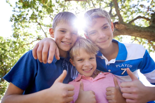 腕の中の兄弟 明るい太陽の下で屋外で遊んでいる間に3人の兄弟が一緒に群がって — ストック写真