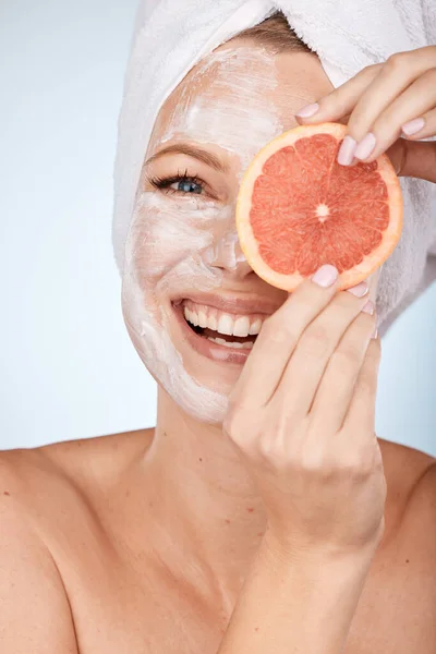 グレープフルーツのスキンケア 美容マスクと顔のデトックス 自然食品と灰色のスタジオの背景に対する幸せなアプリケーションを持つ女性 皮膚科用果物モデルのにきび 製品と顔の肖像画 — ストック写真