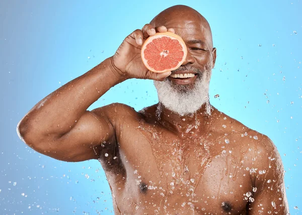 Stock image Beauty, water splash or senior black man with grapefruit for body care, healthcare or skincare health. Happy face, smile or facial portrait of elderly male cleaning, shower or healthy skin wellness.