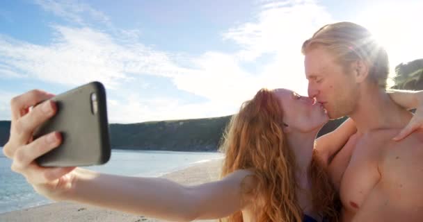 부부는 해변에서 셀카를 로맨스를 키스를 스마트폰을 이용해 사랑하고 행복하게 지내며 — 비디오