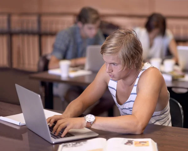 为我的下一篇文章做研究 在图书馆读书时使用笔记本电脑的年轻大学生 — 图库照片