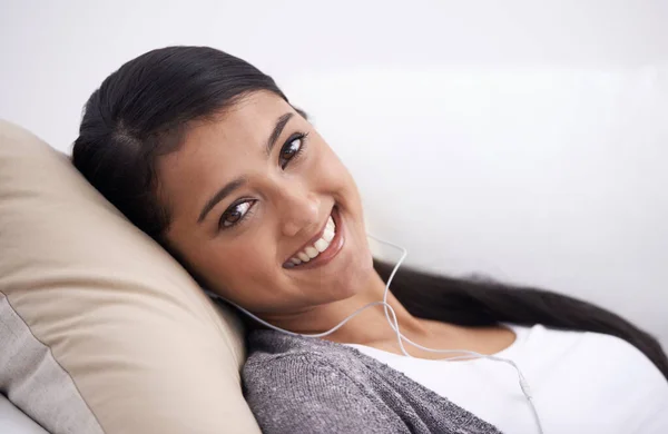 休息とリラクゼーションのビットで取得します 音楽を聴きながらソファに寝そべっている若い女性 — ストック写真