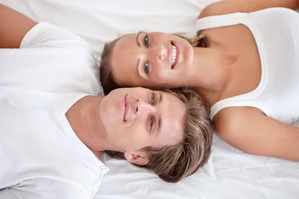 リラックスした瞬間をお楽しみください ベッドの上に寝そべって目を上げる若いカップルの作物のビュー — ストック写真