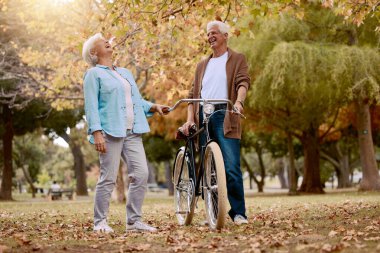 Doğa, kahkaha ve bisikletiyle sonbahar parkında eğlenceli romantik bir buluşma, açık hava barışı ya da özgürlük için seyahat eden yaşlı çift. Aşk, emeklilik bağı ve bisiklet süren gülen kadın ve erkek..