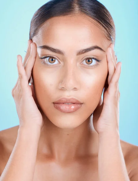 Portrait, face and beauty with a model black woman touching her skin in studio on a blue background. Skincare, cosmetics and antiaging with an attractive young female posing for natural treatment.