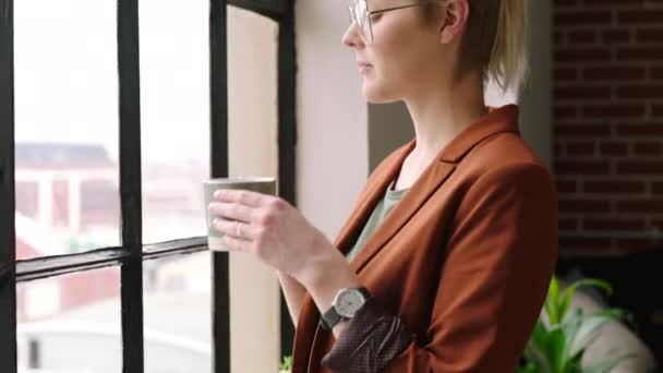 一个女商人在办公室里喝着杯子里的饮料 一边想 一边看 一边喝咖啡 观念和女性员工以一种有远见的心态思考未来的发展 — 图库视频影像