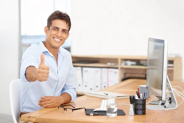 職場に彼の積極性をもたらす 彼の机の後ろに座っている間に親指をあげるハンサムな若いビジネスマン — ストック写真