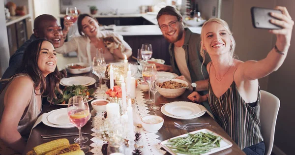 Selfie, dinner and party with friends eating food together for a new year celebration or event. Home, feast and meal with a man and woman friend group sitting at a table for a social gathering.