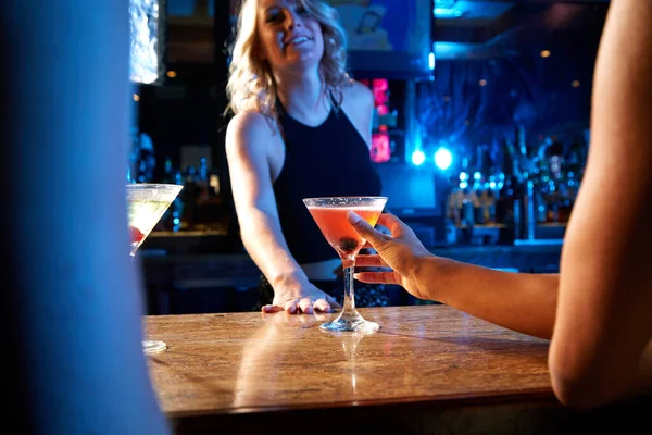 Bartender, nightclub and cocktail drink with mixologist worker at counter serving alcohol at a restaurant, bar or new years party. Hand of woman on glass for drinking, celebration and service.