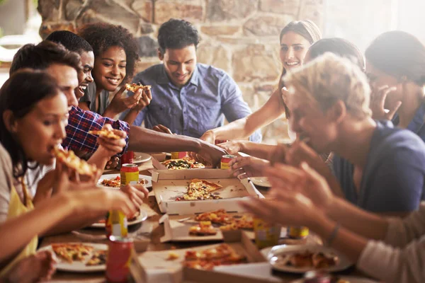 Pizza, dinner party and friends at a restaurant together feeling happy about social celebration. Diversity, food and lens flare of people eating fast food at dinner talking and speaking at a table.
