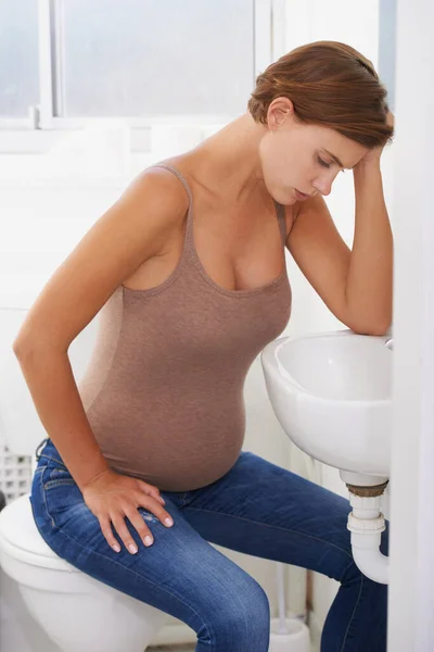 stock image The trials of becoming a mother. A pregnant woman struggling with morning sickness in the bathroom