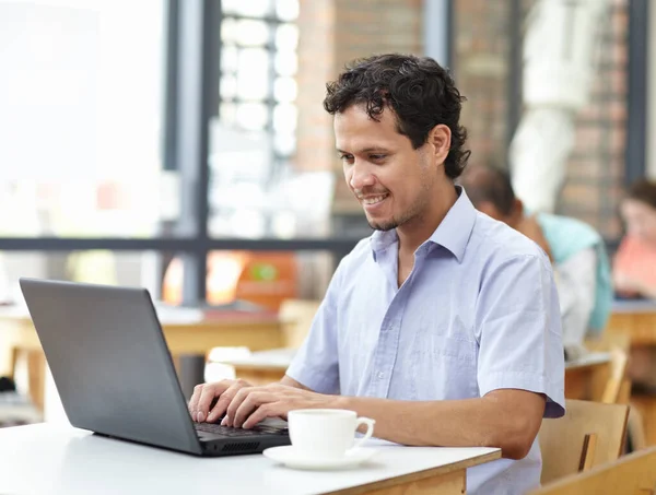 保持专注于咖啡因 坐在咖啡店里在笔记本电脑上工作的年轻人 — 图库照片