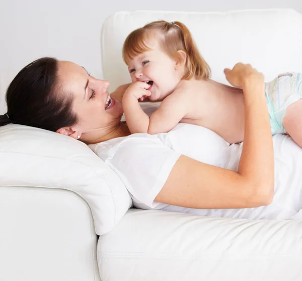 stock image They have so much fun together. A cute little girl lying on her mothers tummy