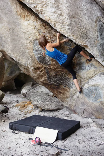 安全上の注意 彼女の下の地面にマットレスで崖の顔を登るロッククライマー — ストック写真