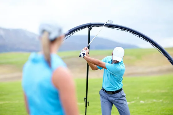 Ensuring she learns the perfect swing. Cropped image of a male coach instructing his female student using a ring to adjust and correct her swing