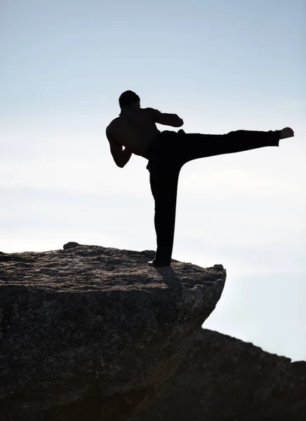 山の中で完璧なテクニック 崖の上を蹴った男のキックボクサー — ストック写真