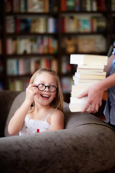 我最喜欢的消遣一个戴着眼镜的可爱小女孩笑着递给她一堆书 — 图库照片