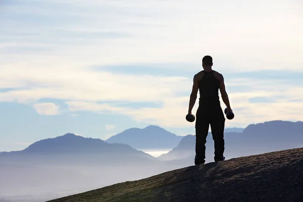 ビューで動作します 山の頂上に立ってダンベルを保持する男のレビュー — ストック写真