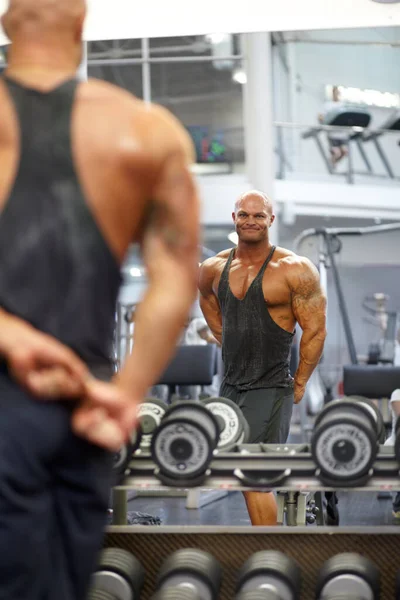 检查他的进展 一位肌肉健美的健美运动员在镜子中观察自己的身体反射时弯曲肌肉 — 图库照片