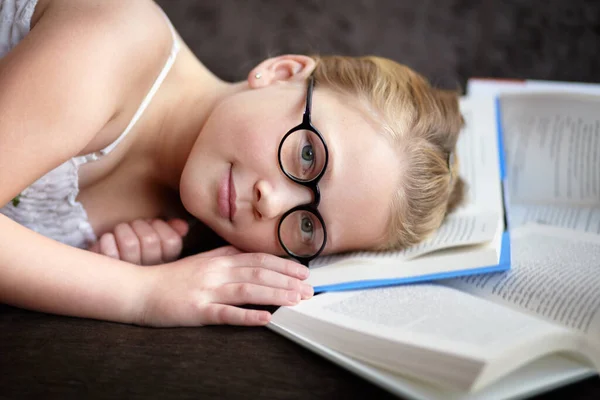 没有什么比一本好书更令人放松的了 一个年轻可爱的金发女郎 头戴眼镜躺在打开的书架上 — 图库照片