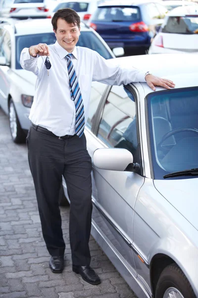 Here are your car keys. A happy car salesman handing you the keys to your new car