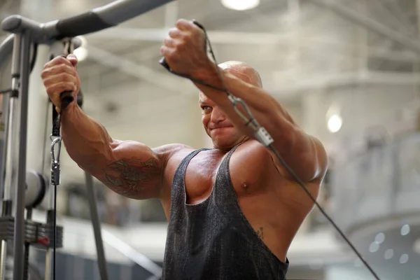 彼は強さと決意を示す ジムでトレーニングするために運動器具を使用して男性のボディービル — ストック写真
