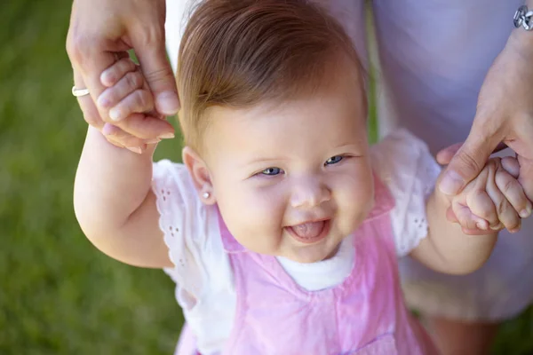 stock image Taking a walk with mom. A cute baby girl walking in the garden while holding her mothers hands