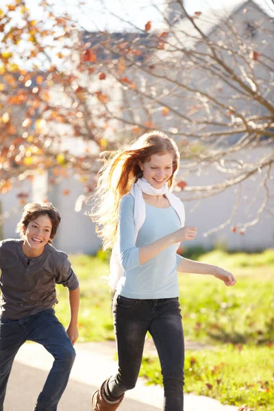 秋の葉を通して凍る 弟と妹が遊んで通りを走っている — ストック写真