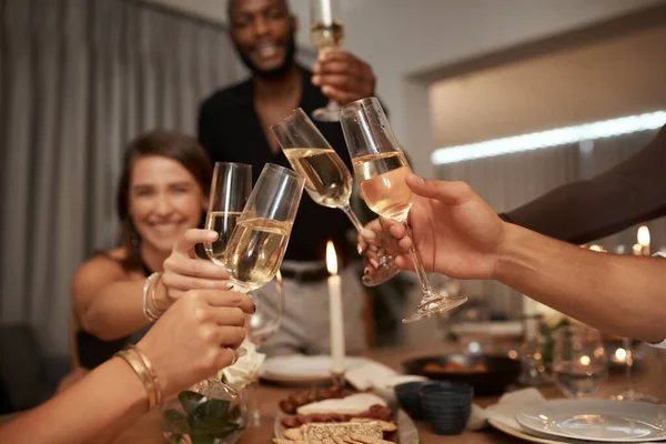 Dinner party, friends and cheers with wine glass for celebration, social gathering or new years event at home. Happy group of people toast alcohol, champagne and drinks to celebrate together at night.