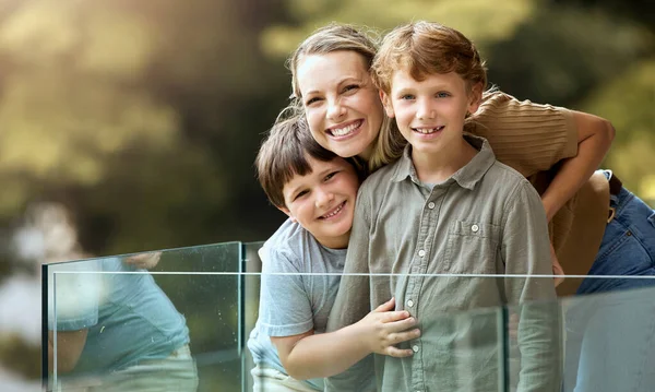 Portrait of a happy caucasian family of three enjoying the view from a balcony at home. Smiling single parent bonding with her sons on vacation together.