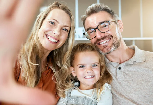 A happy smiling family of three relaxing and spending quality time together in the lounge. Loving caucasian family bonding with their daughter and taking selfies on the sofa at home.