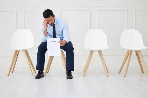 Full length of asian businessman waiting for an interview. One young stressed applicant sitting alone. Sad ethnic professional holding resume in line for job opening, vacancy and opportunity in offic.