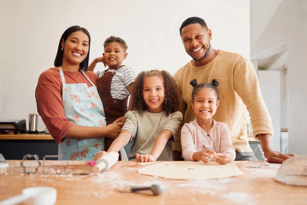 A happy mixed race family of five relaxing and cooking together. Loving black family being playful while baking together. Young couple bonding with their foster kids at home in a messy kitchen.