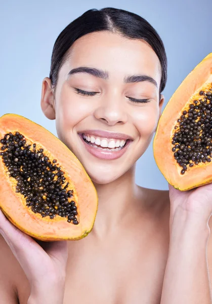 stock image A happy smiling mixed race woman holding a papaya. Hispanic model promoting the skin benefits of a healthy diet against a blue copyspace background.