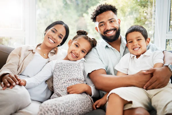 Portrait of a young hispanic family happily bonding together on the sofa at home. Mixed race mother and father sitting of the couch in the loung and looking happy while bonding with their cute little.